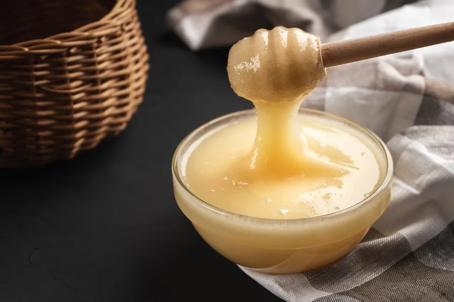 Clover honey in a small glass bowl with wooden dipper