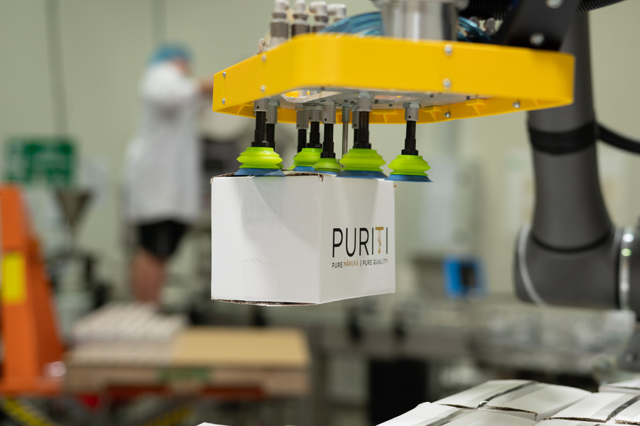 Honey carton being transported to pallet with robotic arm