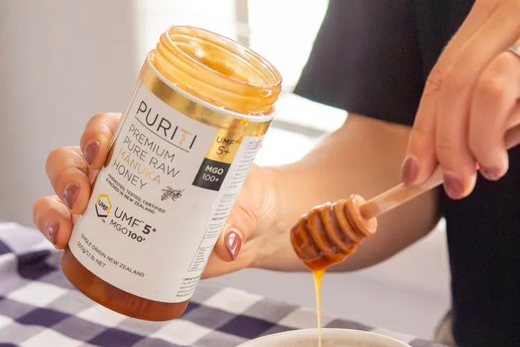 Women holding Puriti honey UMF 5+ and wooden dipper