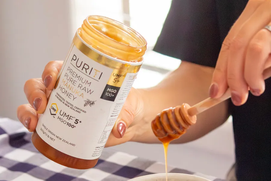 Women holding Puriti honey UMF 5+ and wooden dipper