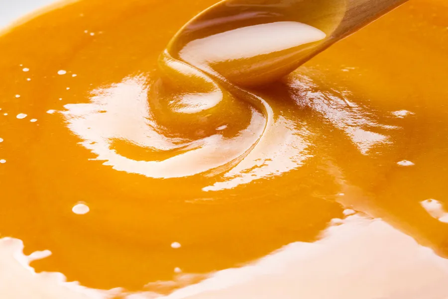 Manuka honey being stirred with wooden spoon