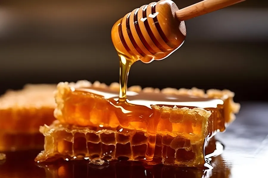 Honey dipper with honey dripping onto honey comb
