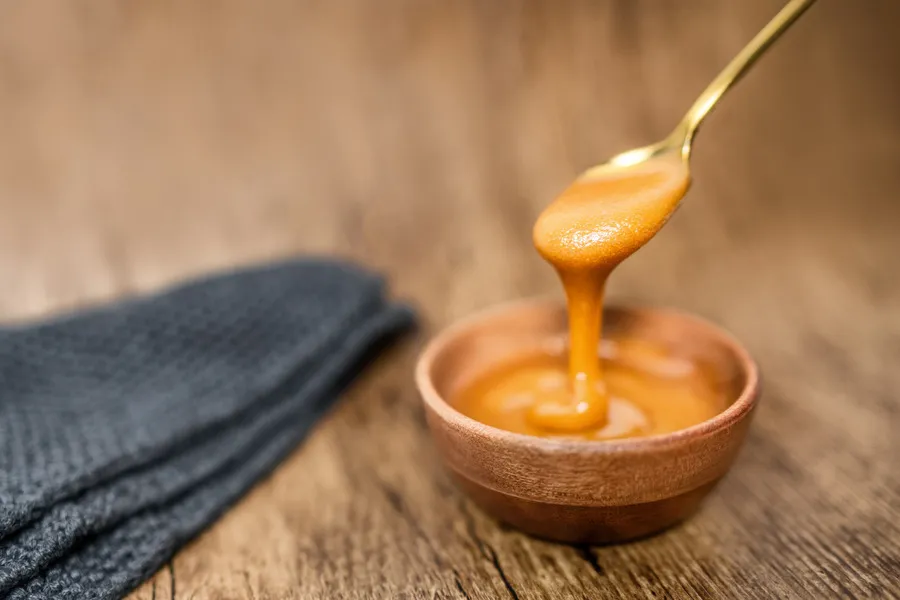 Manuka honey in wooden bowl and spoon on wooden table