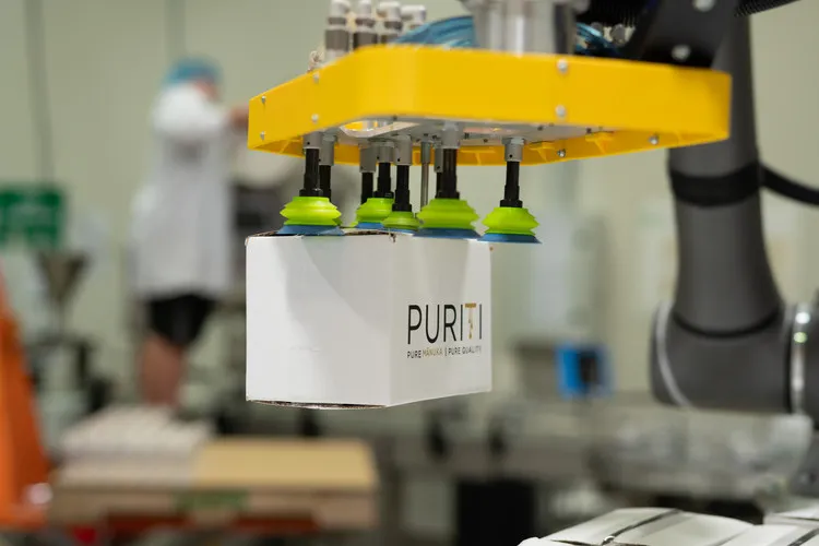 Robotic arm moving carton of Puriti Manuka Honey onto pallet