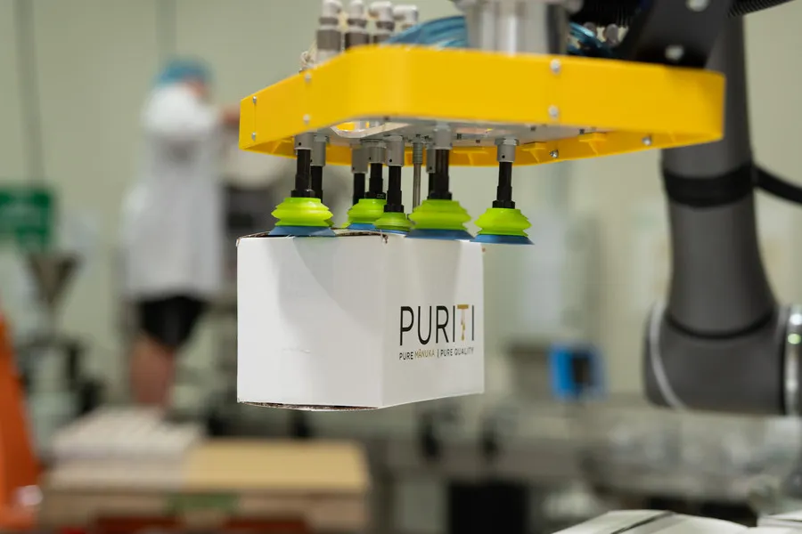 Robotic arm moving carton of Puriti Manuka Honey onto pallet