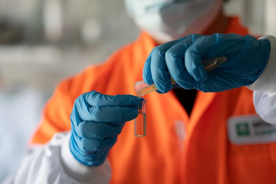 Technician pouring honey from a test tube for testing
