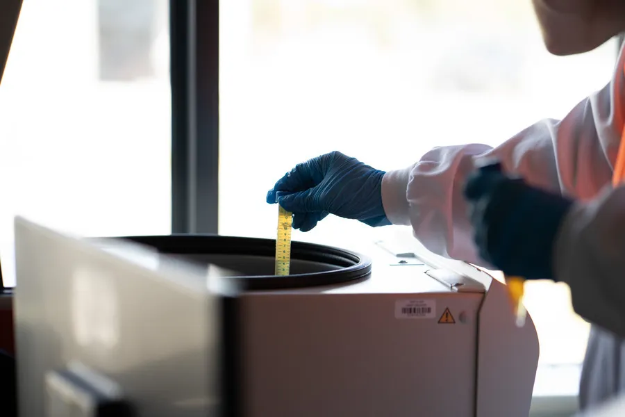 Technician placing test tube of Manuka honey being placed in testing machine