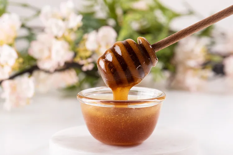 Manuka honey is a glass bowl with wooden dipper