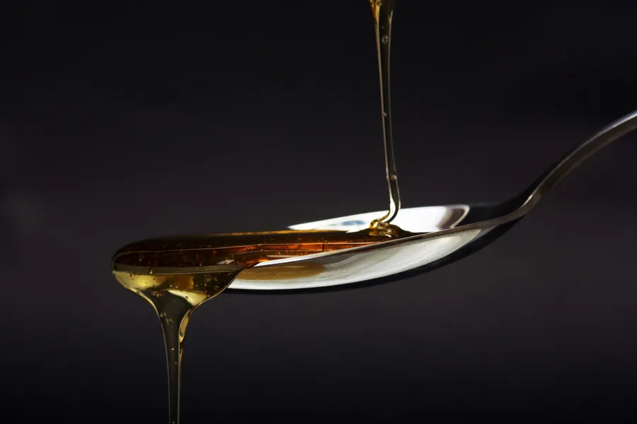 Manuka honey dripping of spoon with dark background