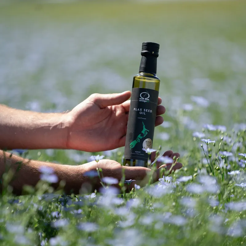 OmegaNZ Flaxseed Oil bottle in a flowering flaxseed crop