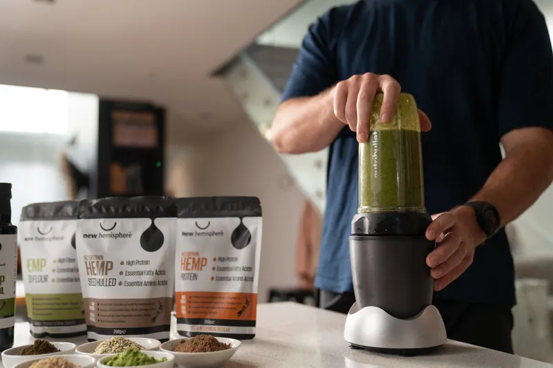Man making a green smoothie with Hemp Heart, Hemp Protein and Hemp Flour in the foreground