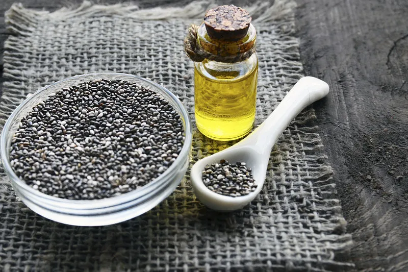 Chia seed oil in small jar with small glass bowl of chia seeds beside it