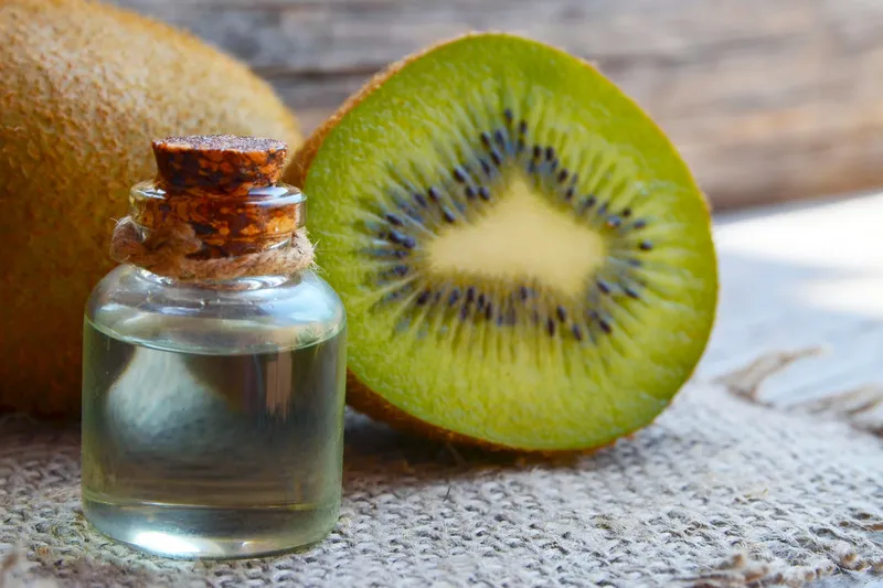 Small jar of kiwifruit seed oil with half a kiwifruit beside it