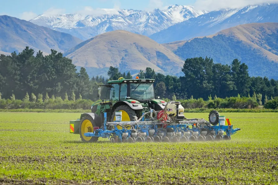 Tractor planting seed with mountains in the background