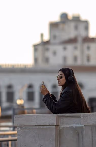 Woman with headphones and sunglasses using phone outdoors.