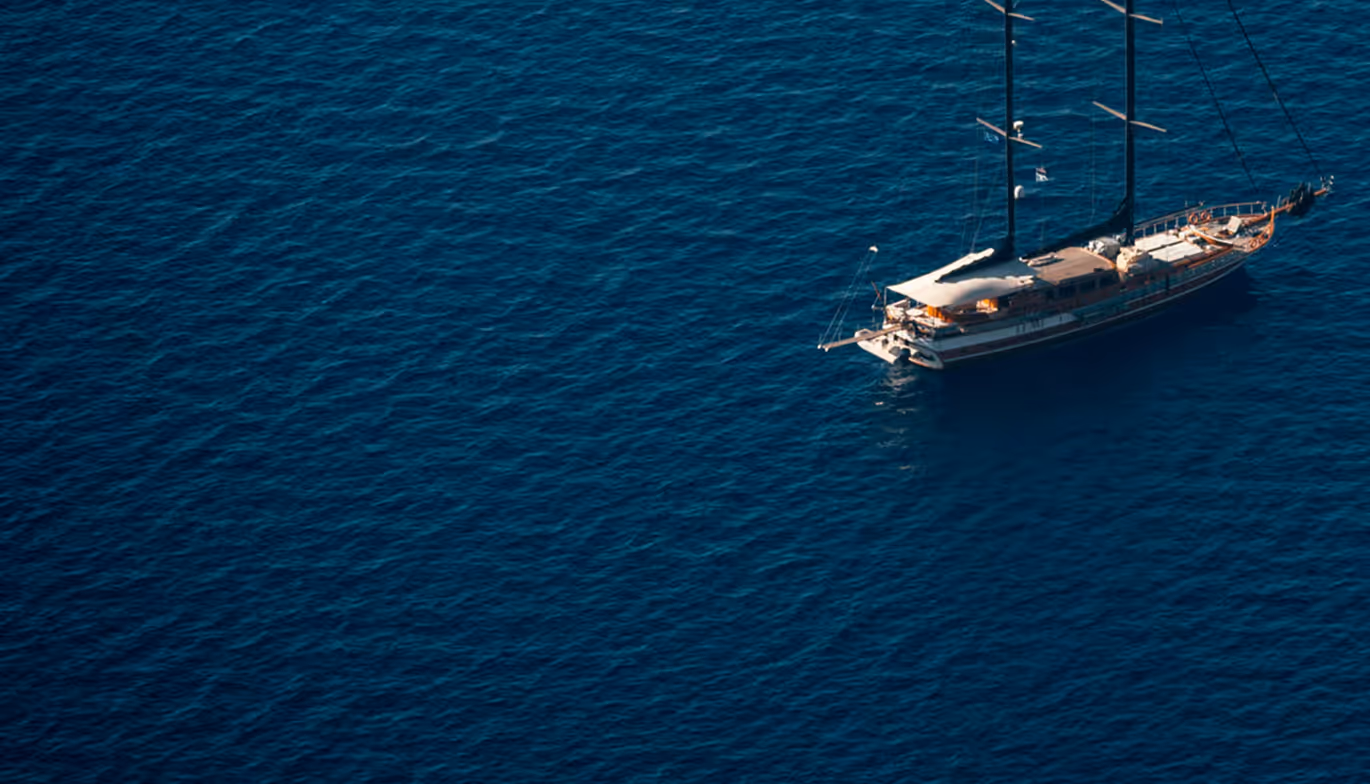 Sailboat with two masts floating on deep blue sea water.