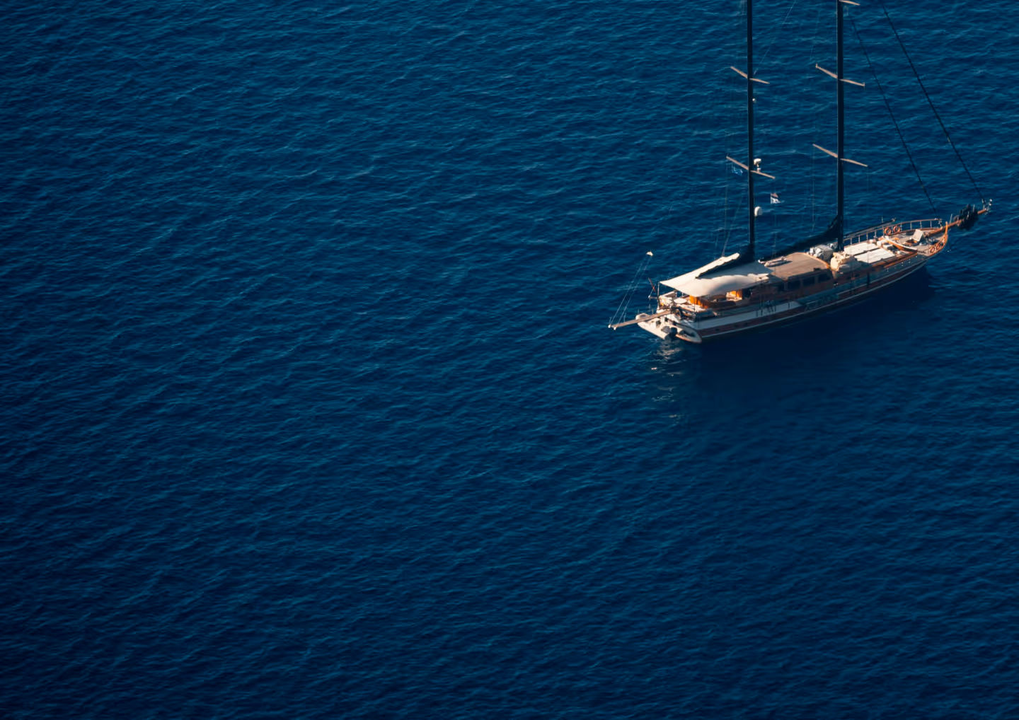 Sailboat with two masts floating on deep blue sea water.