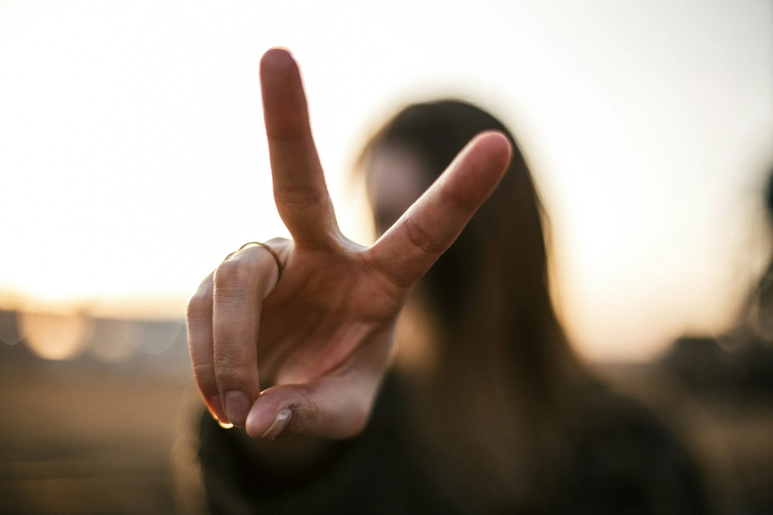 Stock image of a person giving the peace sign.