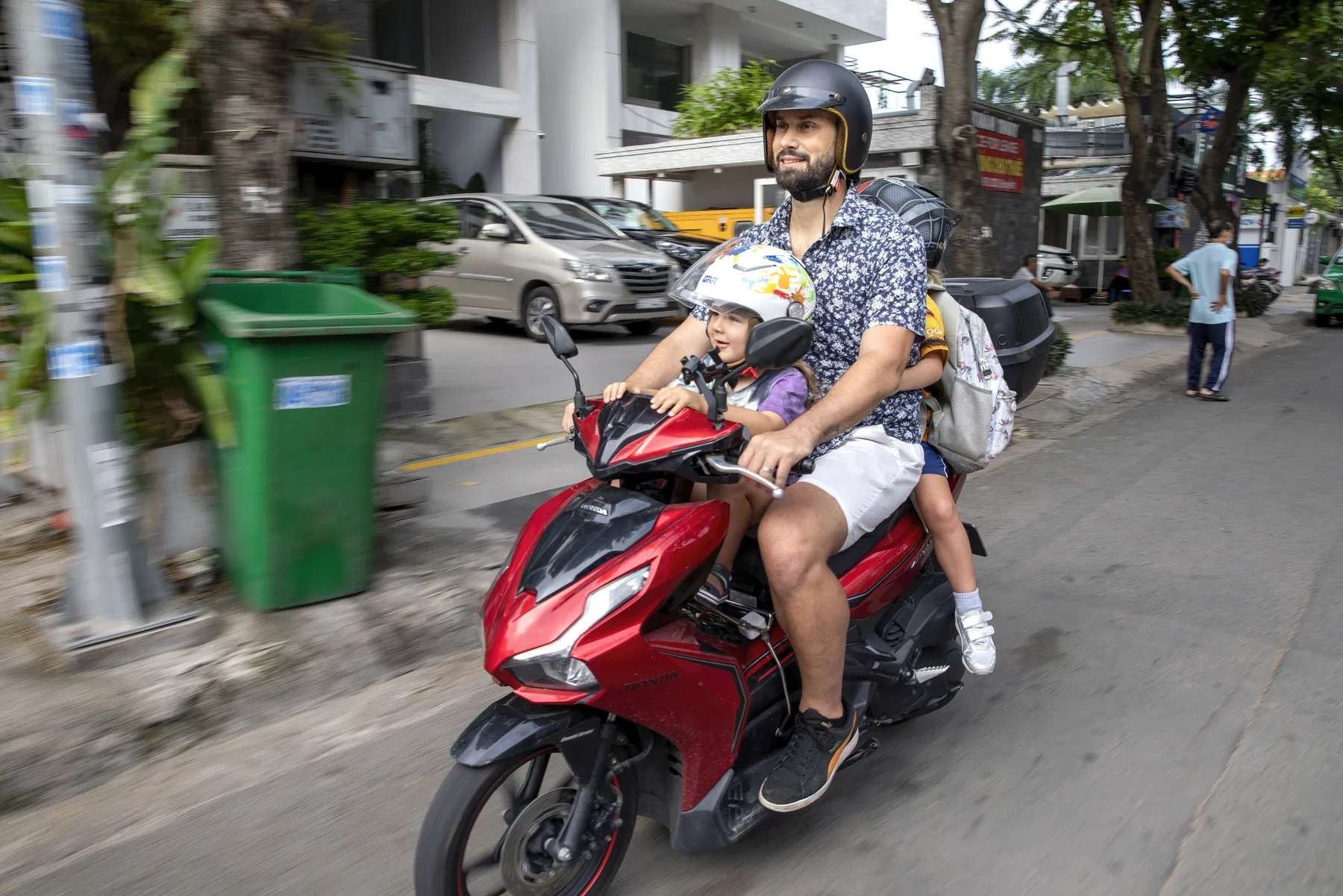A man driving children on a motorbike.