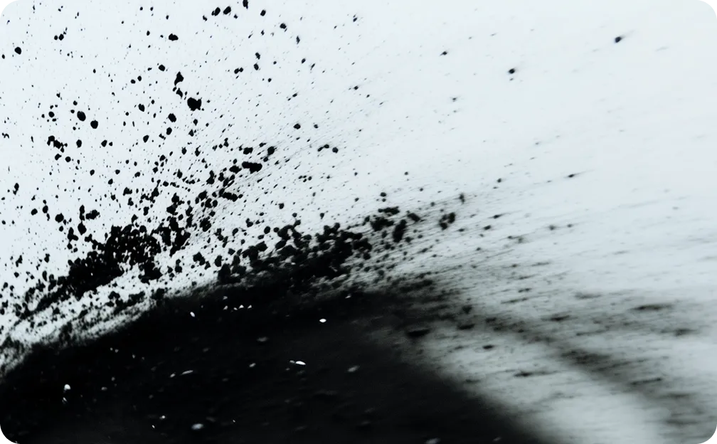 Black ink splattered and spreading dynamically on a light surface.