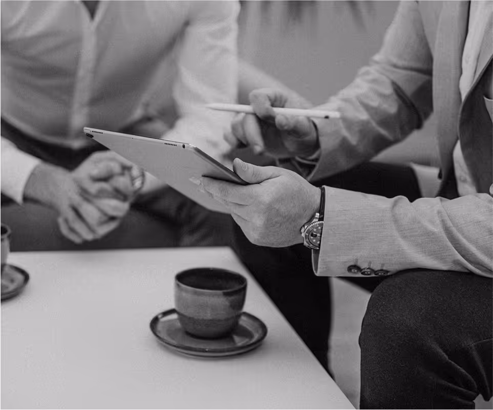 Deux personnes en réunion informelle, l’une tenant une tablette et un stylet, avec des tasses de café posées sur la table.