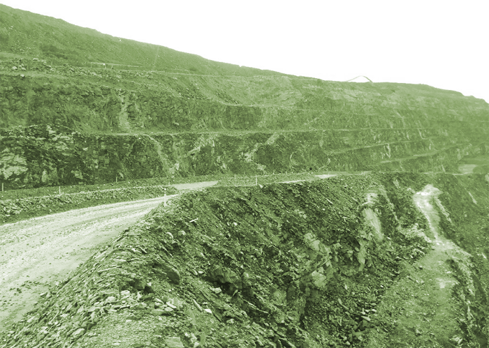 Terraced rocky pit walls with a dirt road winding through a mining site