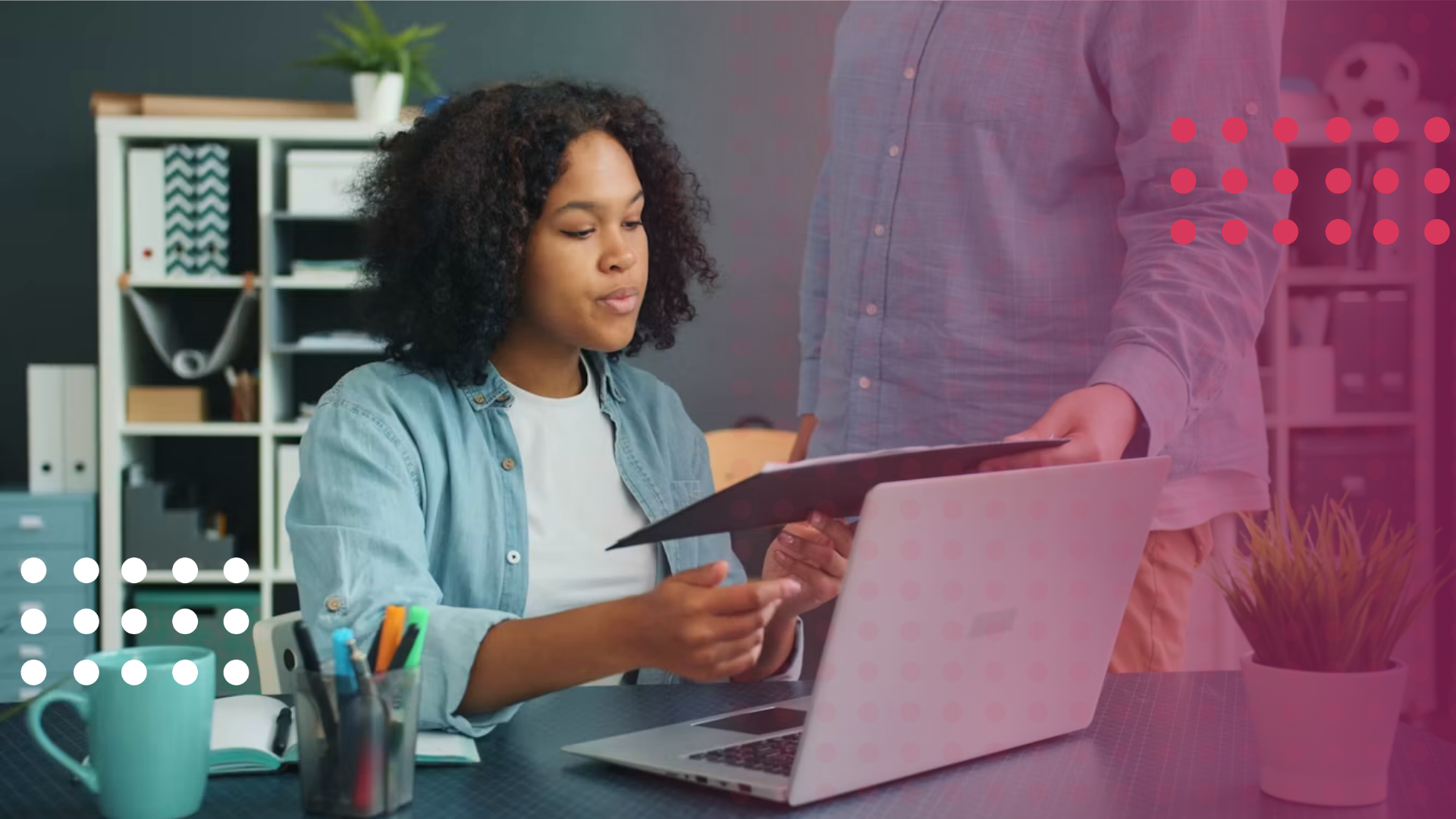 Two colleagues reviewing a document at a desk, with a laptop open in front of them