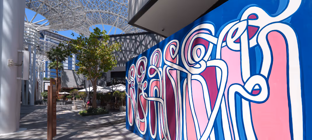 Colorful abstract mural in a modern plaza with a geometric dome roof.