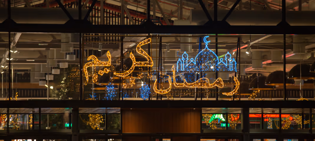 Illuminated "Ramadan Kareem" sign with a blue mosque outline glowing at night.