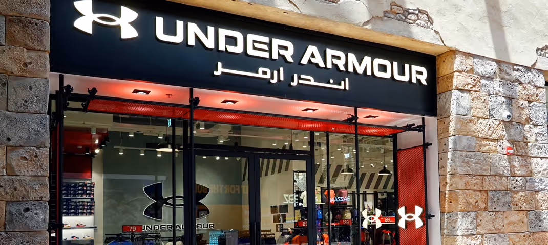Exterior of an Under Armour store featuring the brand name in English and Arabic.