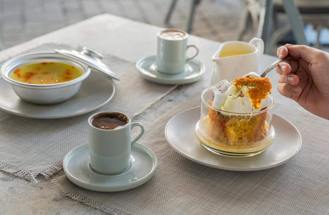 Various coffees and cakes on a table, including a fruit tart and carrot cake.