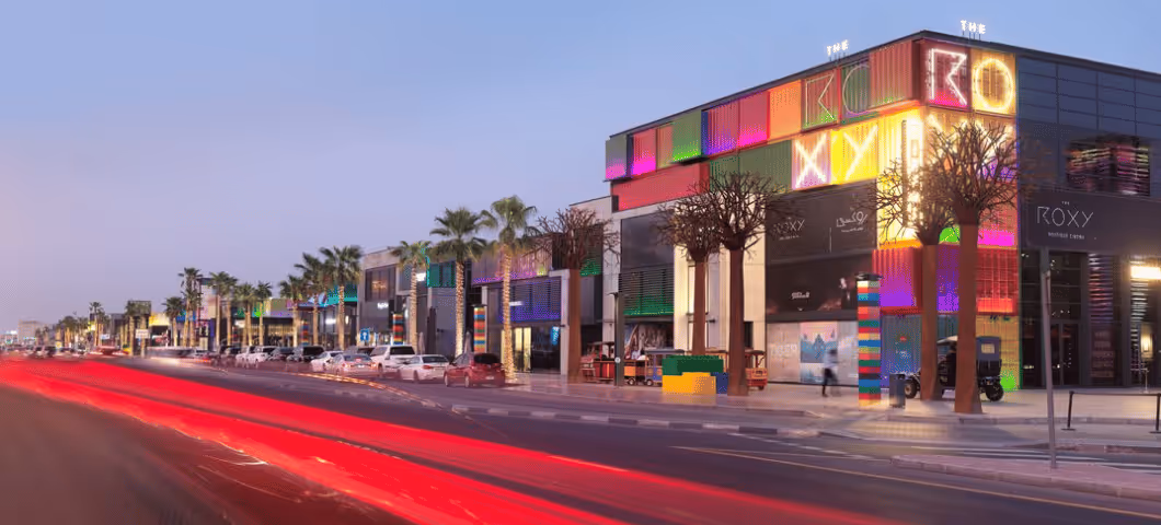 Vibrant street scene at dusk featuring the colorful Roxy Cinema building at Boxpark and palm trees