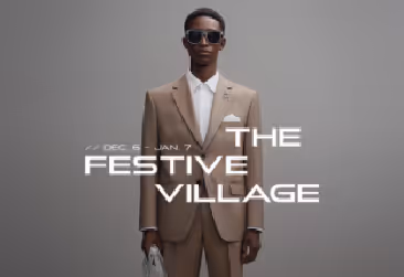 A man in a tan suit and sunglasses posing for "The Festive Village" advertisement.