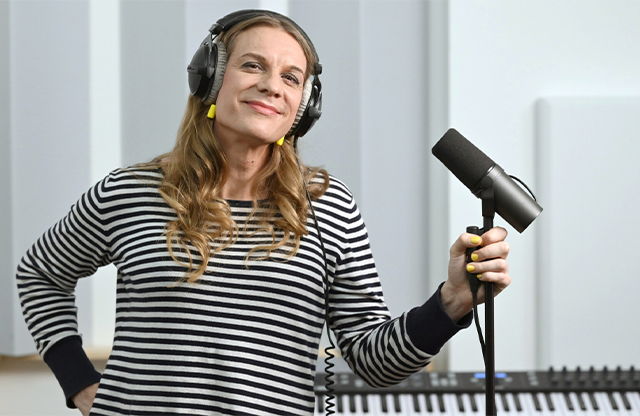An image of Philippa Jarke who is the new corporate voice for the BVG in Berlin- Philippa smiles into the camera and has a microphone in her left hand. She is in the studio with why do birds, the sound branding agency that casted her.