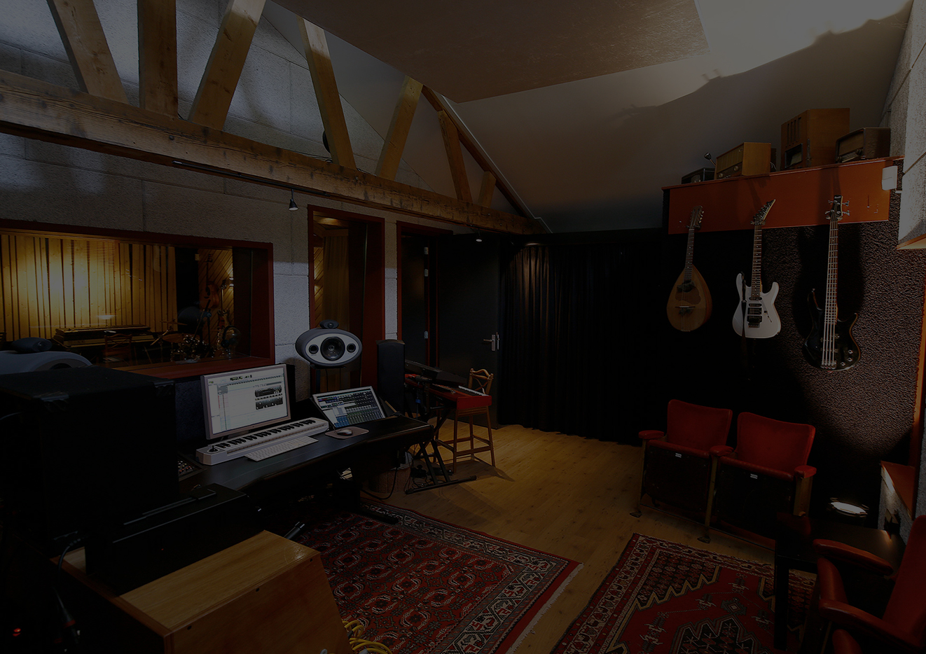 De regieruimte van Studio A60 met gitaren aan de wand en rode bioscoopstoelen