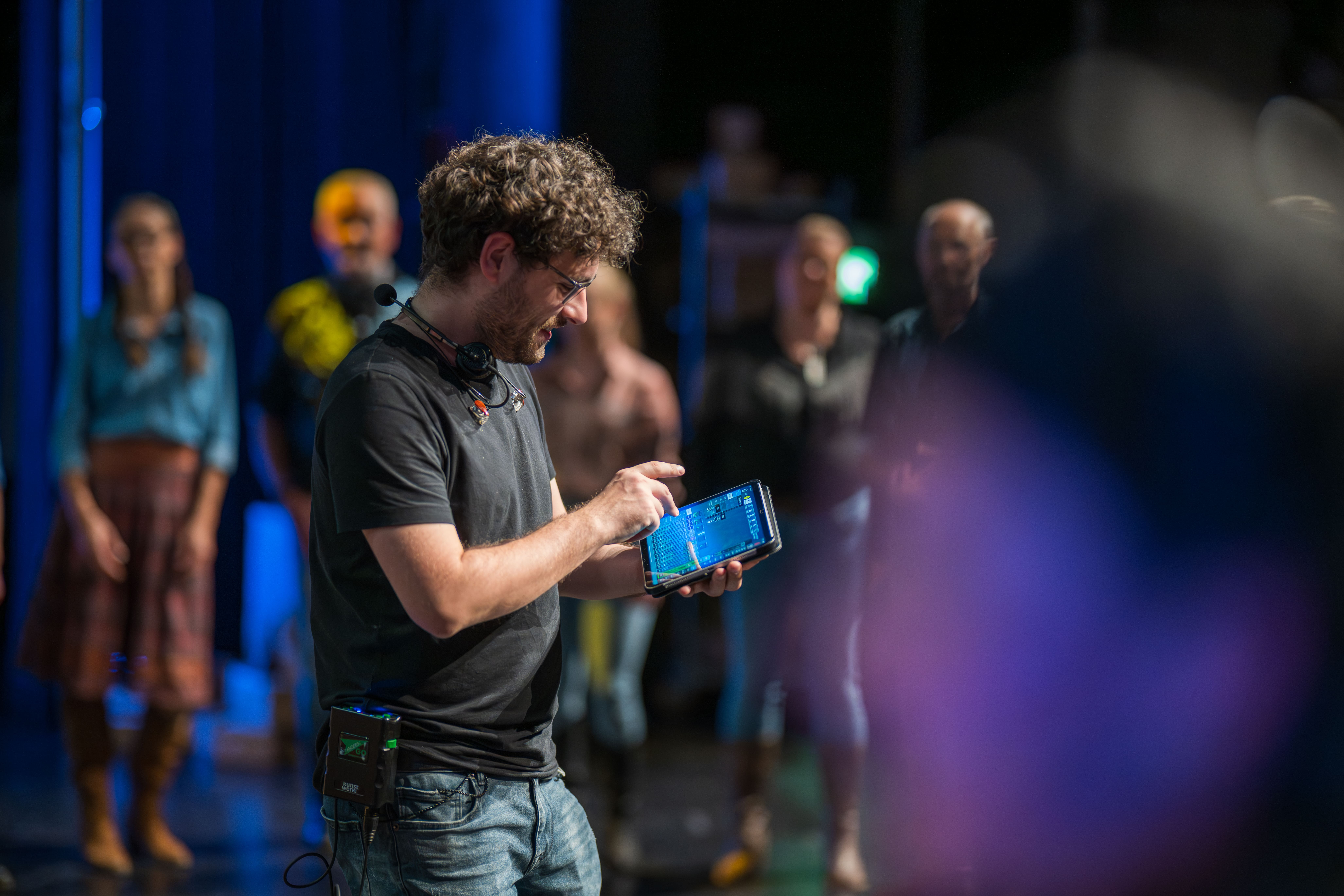 Geluidstechnicus met tablet aan het werk op het podium tijdens een voorstelling