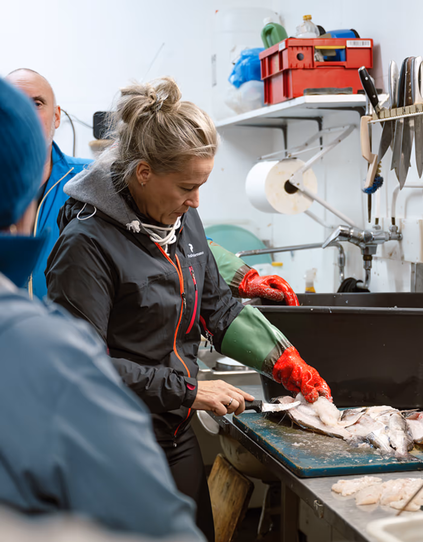 Under bedriftssamling renser deltaker fangsten i naust ved havet – ekte kystkultur i Vesterålen nær Skagenhaugen.