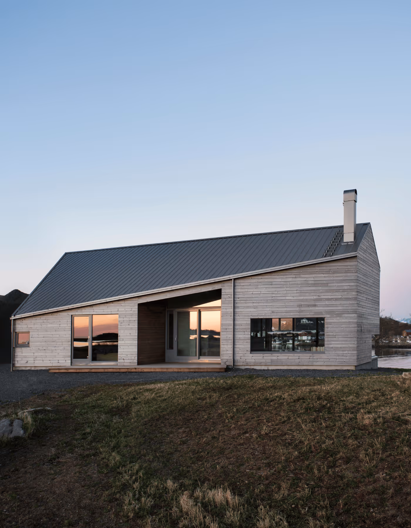 Arkitekttegnet hovedhus på Skagenhaugen i Vesterålen badet i kveldssol, med utsikt mot hav og natur.