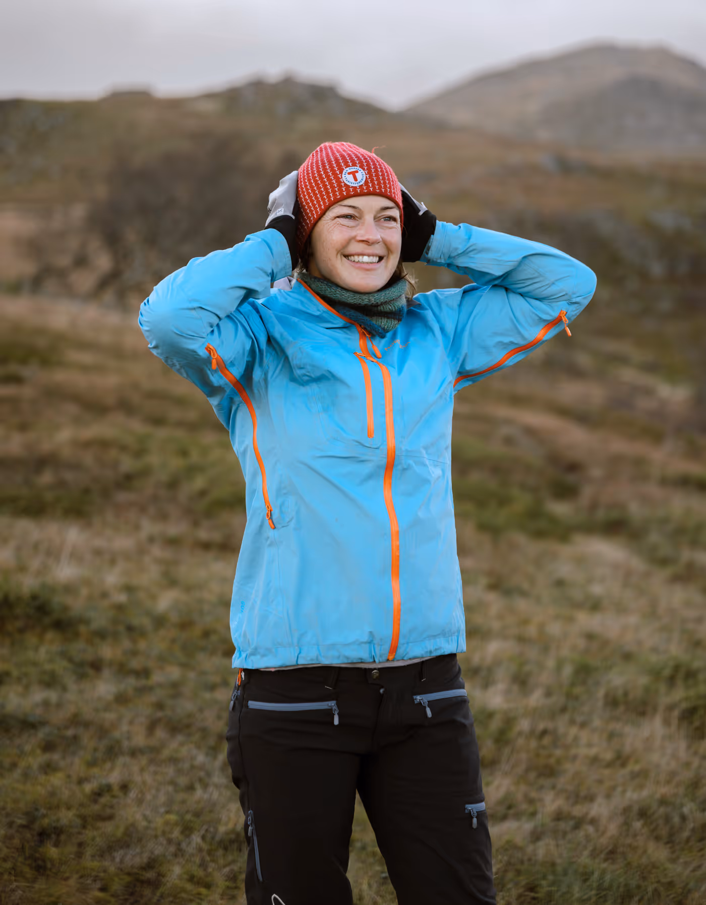 Smilende kvinne i blå turjakke nyter frisk fjelluft i Vesterålen – energi fra nordnorsk natur.