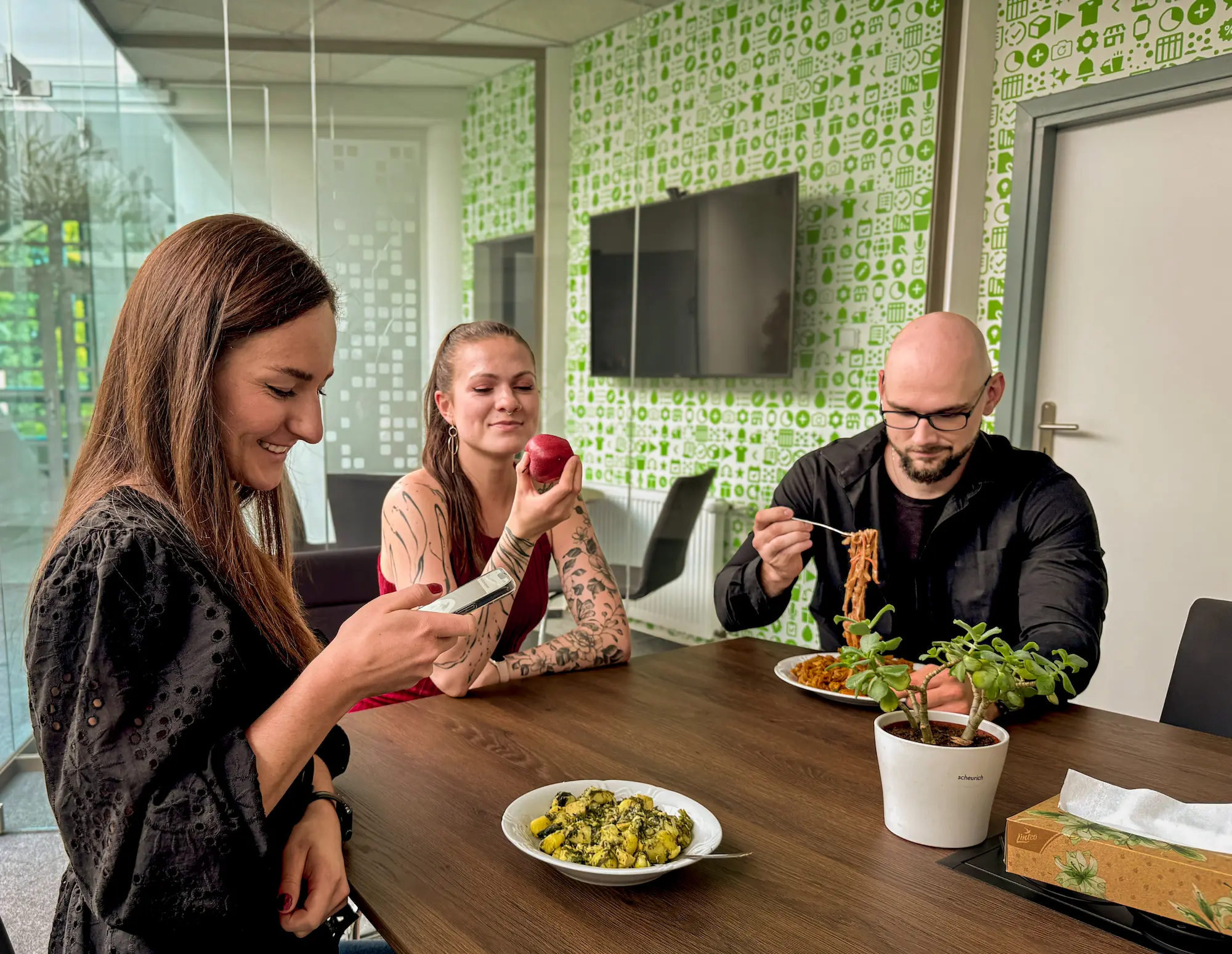 Tři lidé u oběda používají aplikaci Kalorické Tabulky