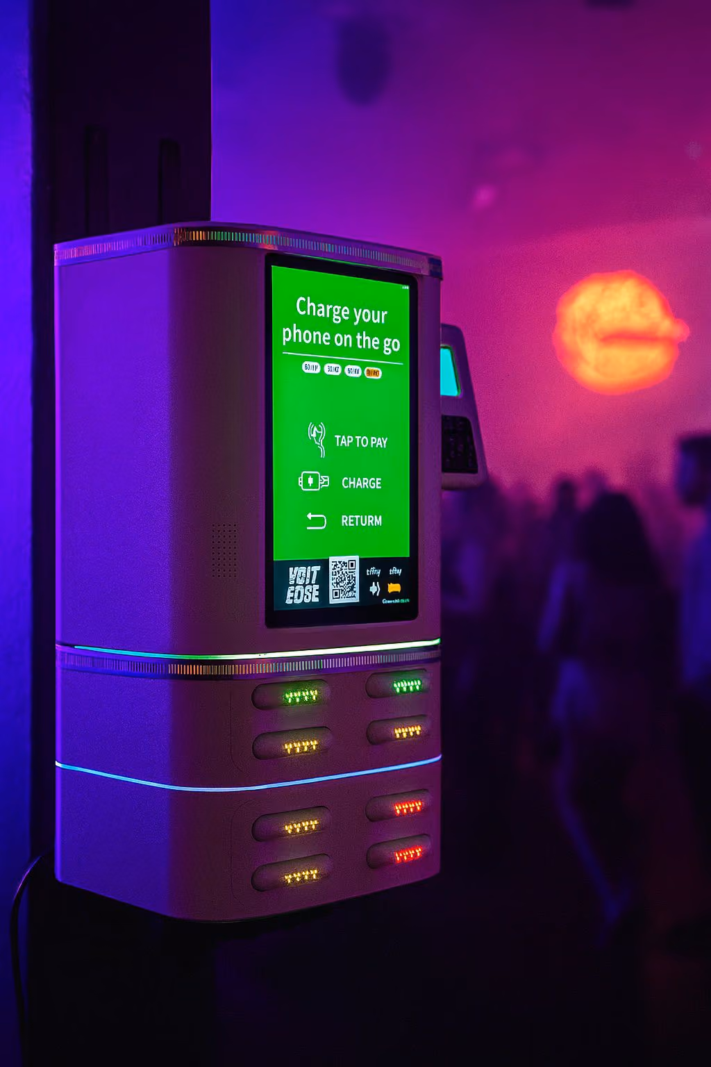 Phone charging kiosk with green screen instructions in a dark setting with colorful lighting.