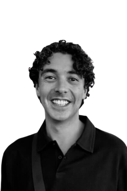 Portrait of a man in a suit and patterned tie with a pocket square, smiling slightly.