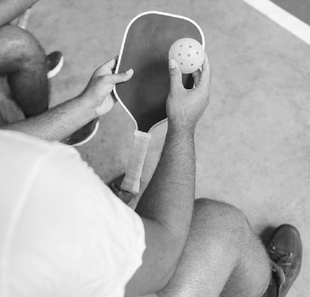 Person holding a pickleball paddle while wearing Crocs with socks