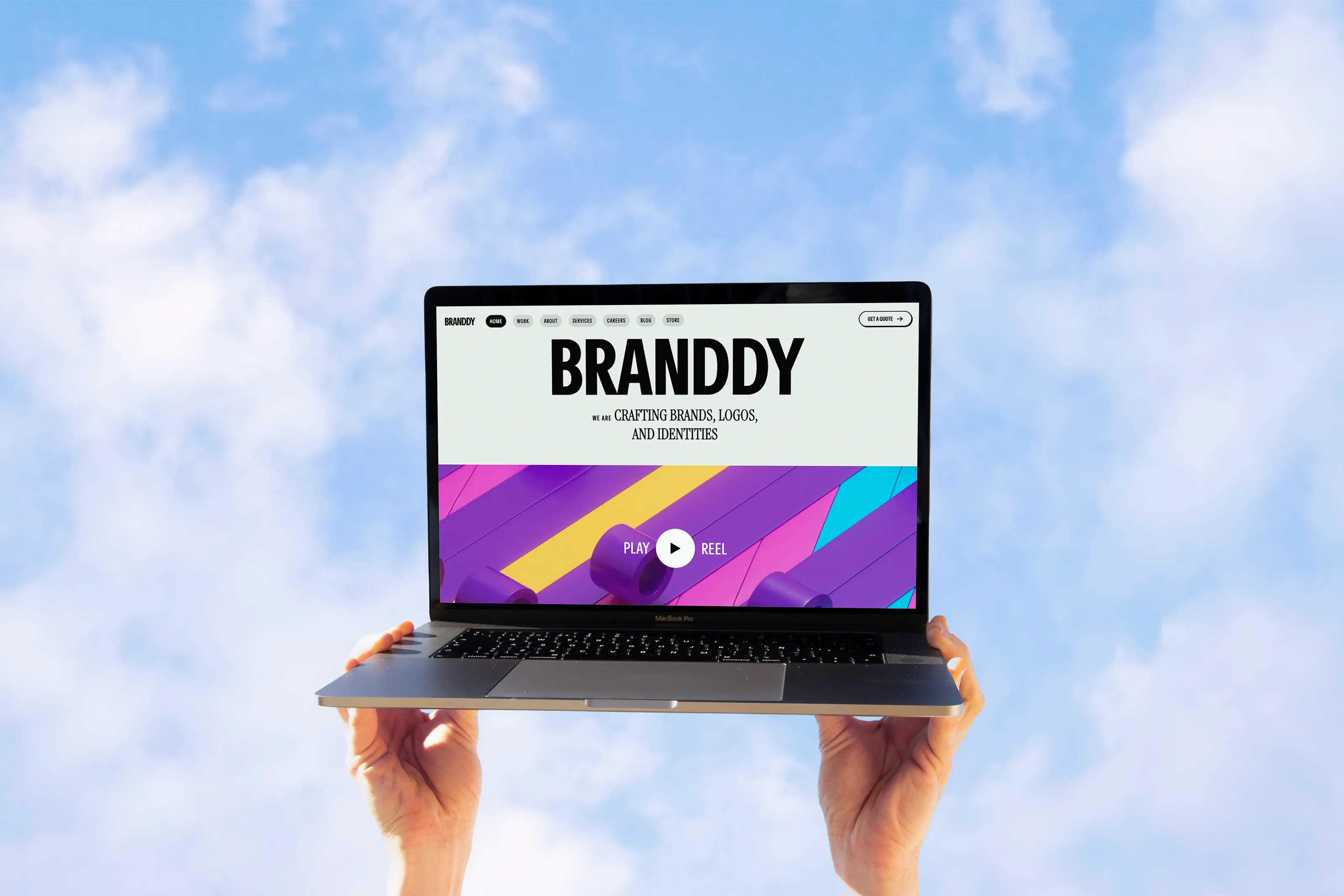 Ordinateur portable tenu vers le ciel avec un site affiché, symbole de créativité et d’élévation digitale.