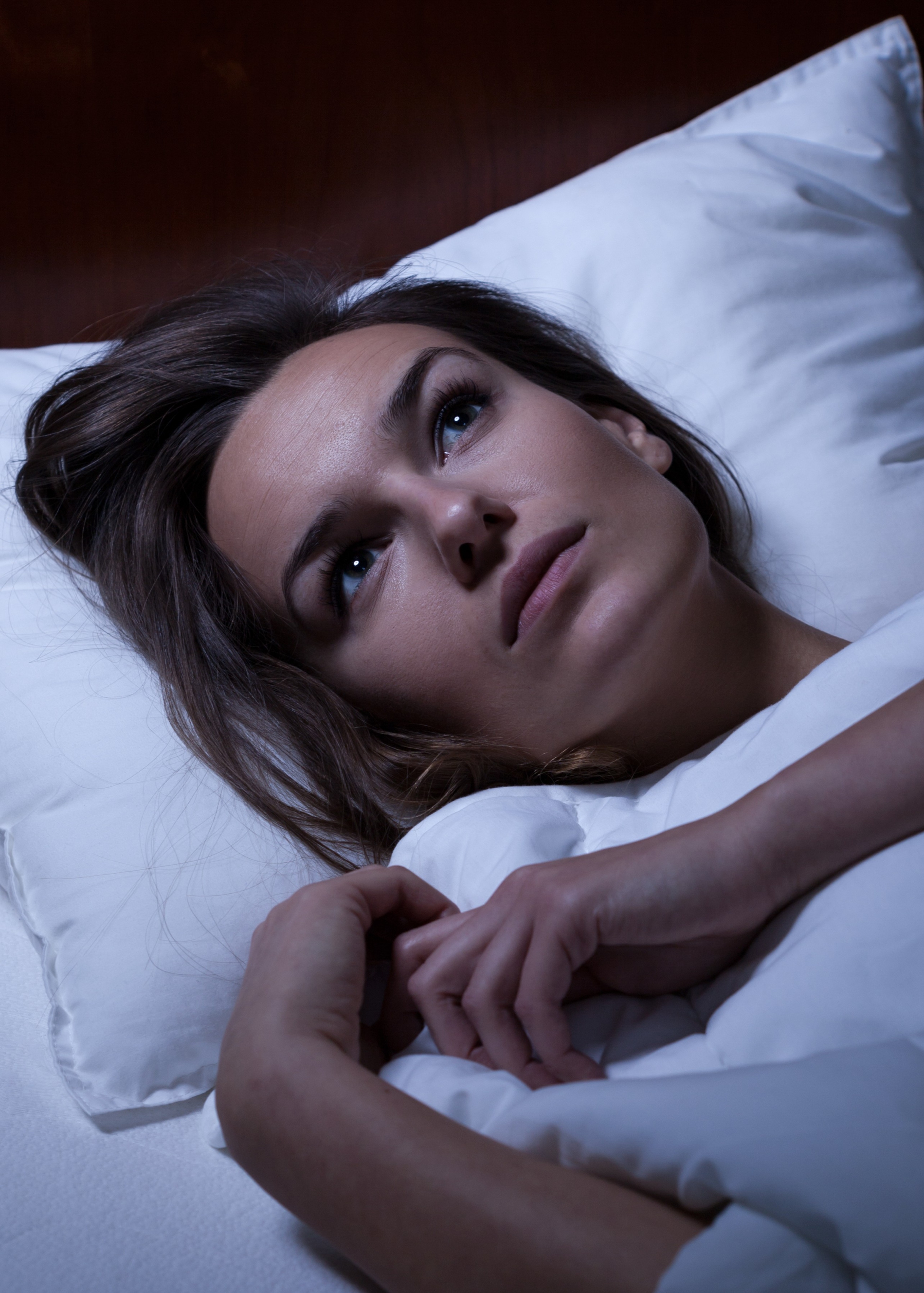 A woman laying in a bed with white sheets.