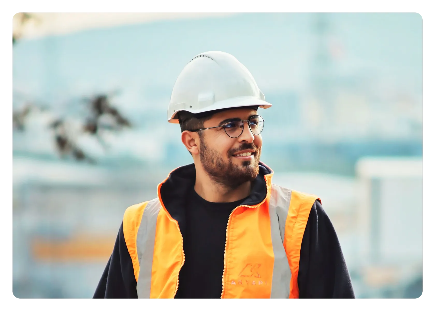 A construction worker wearing a hard hat and high-visibility vest on site.