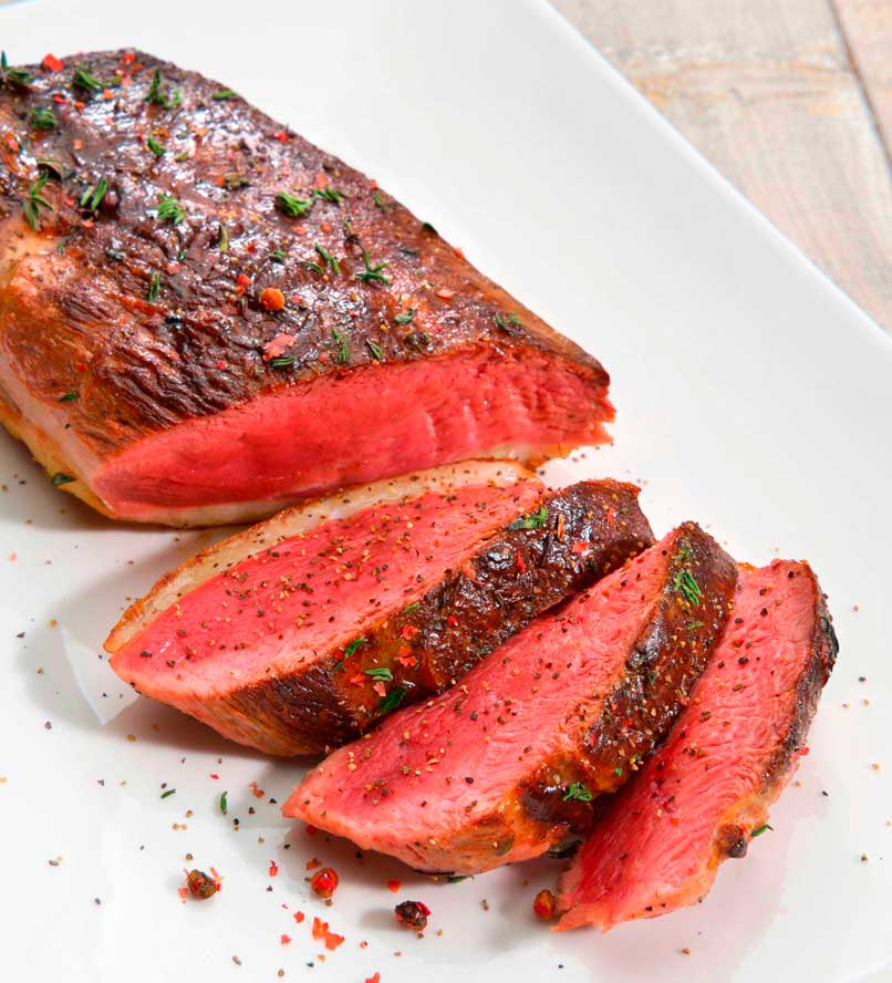 A white plate holds pieces of meat that have been neatly cut into smaller portions.