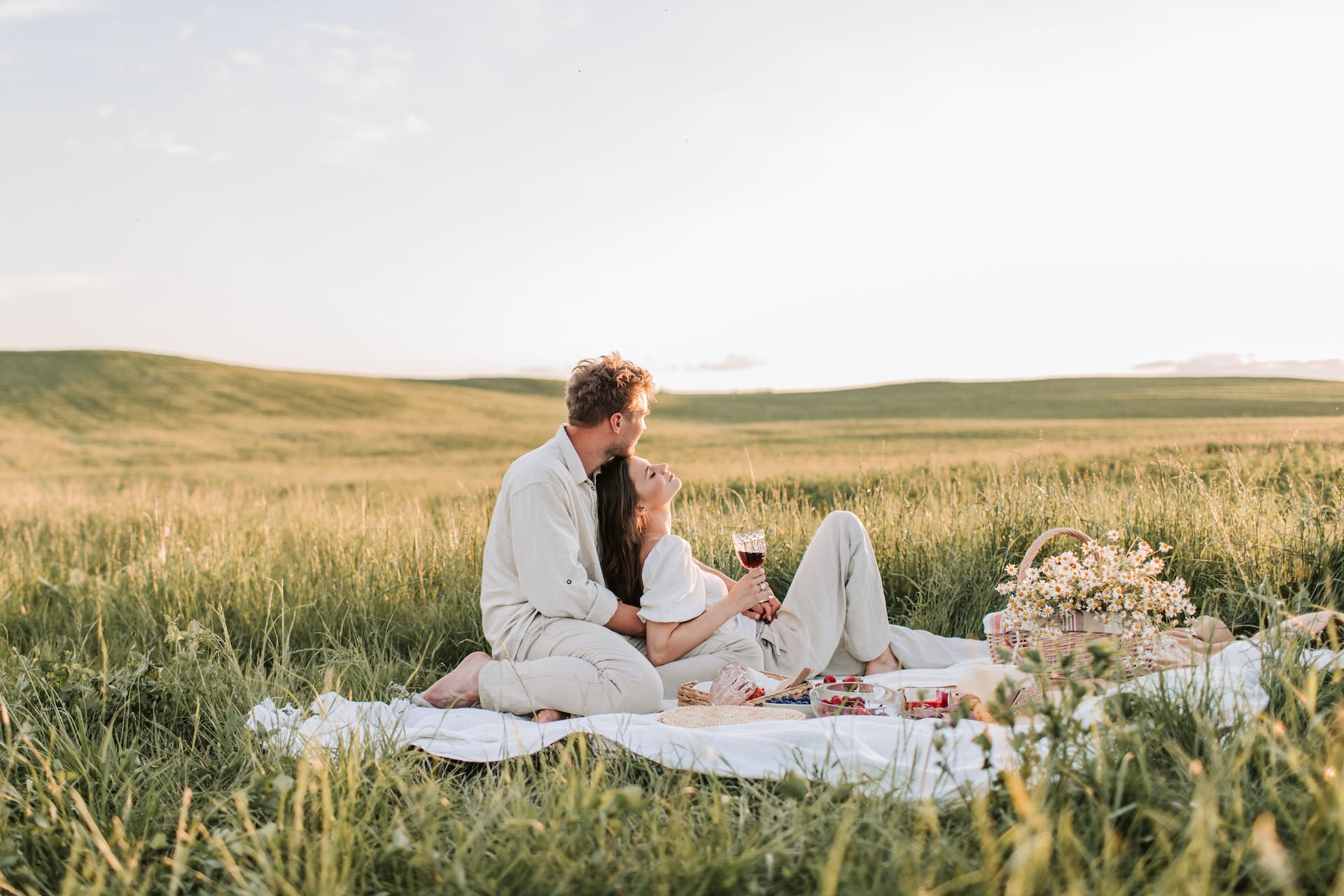 Couple laying on a picnic blanket in a field