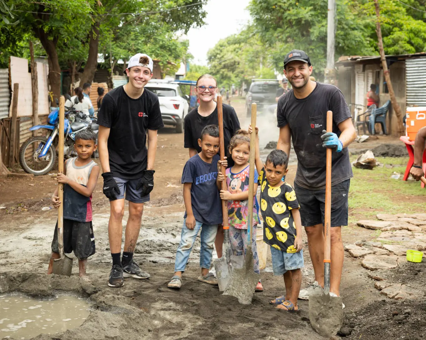 Christ Fellowship students and local kids holding shovels at a community build
