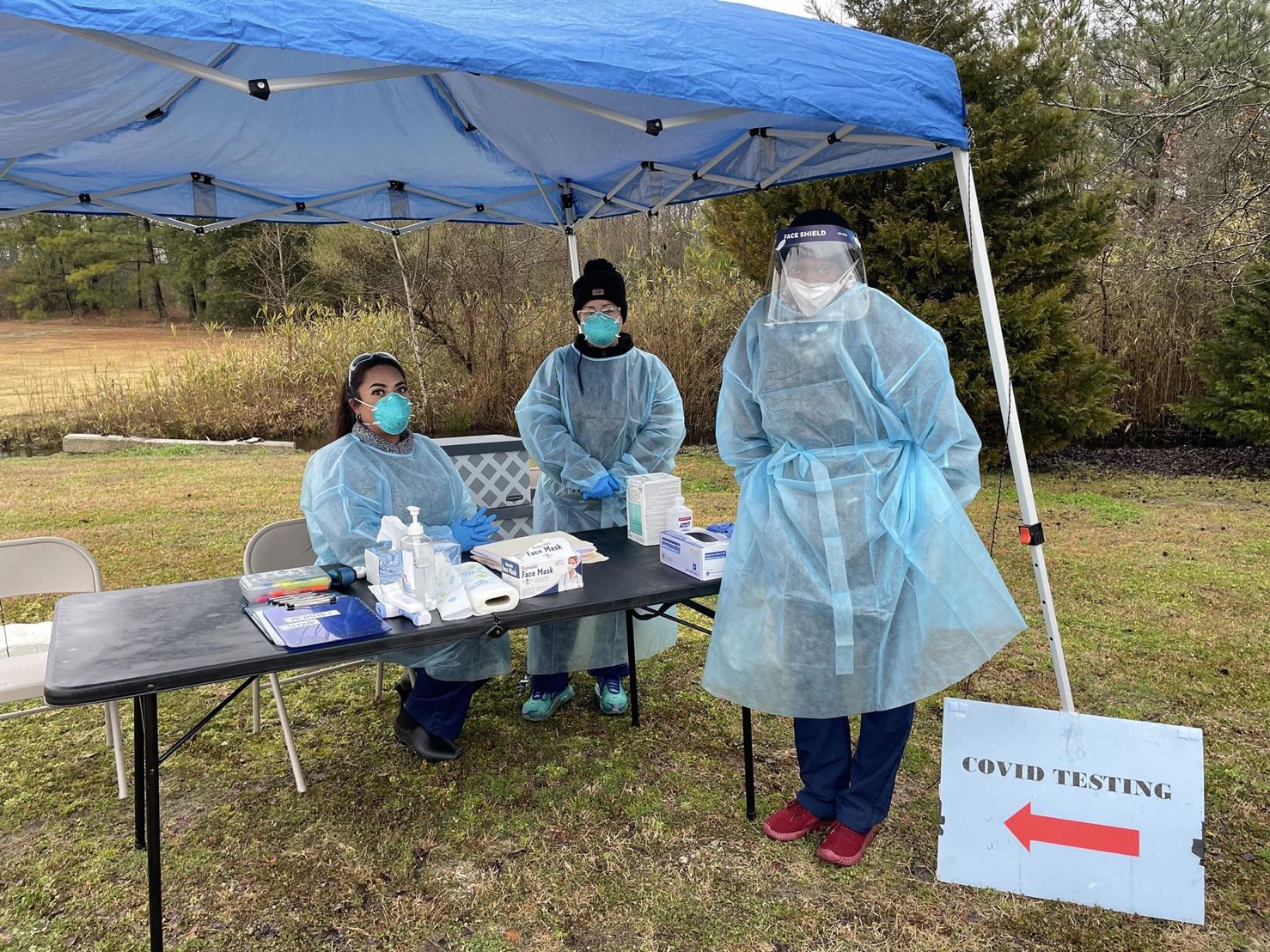 Healthcare professional administering a vaccine to a woman with a young girl watching.